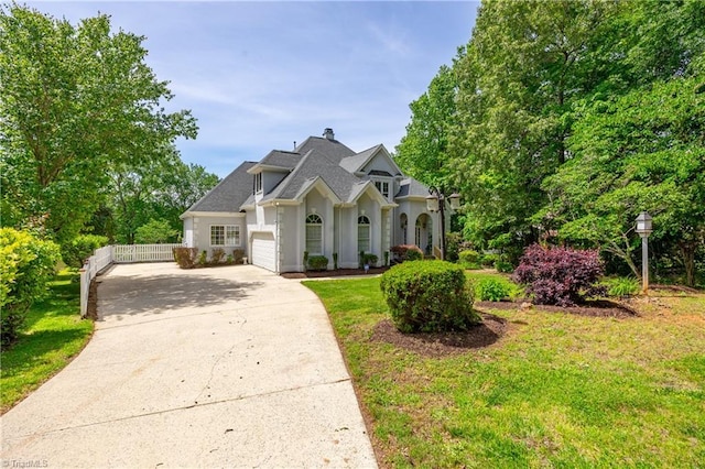 view of front of home with a garage, driveway, stucco siding, and a chimney
