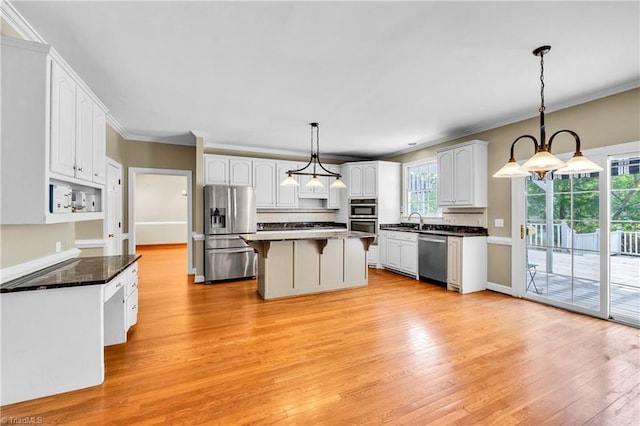 kitchen with appliances with stainless steel finishes, white cabinetry, ornamental molding, light wood-style flooring, and a breakfast bar