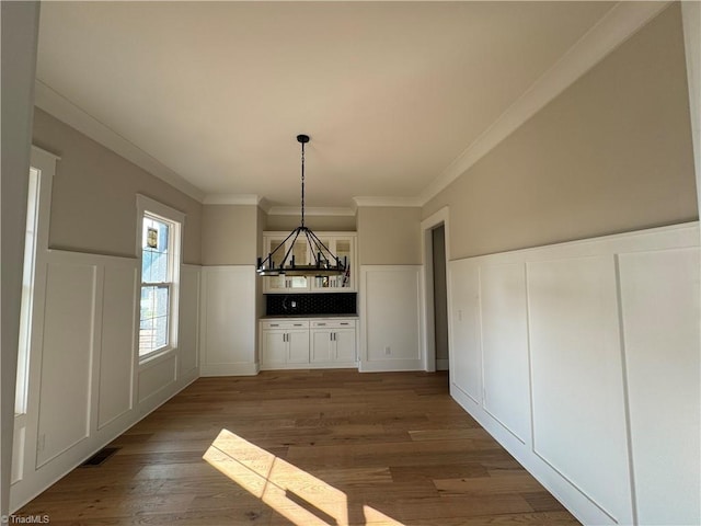 unfurnished dining area featuring an inviting chandelier, dark hardwood / wood-style floors, and ornamental molding