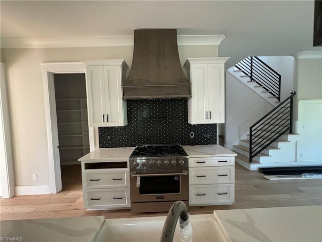 kitchen featuring white cabinetry, high end stainless steel range, tasteful backsplash, light hardwood / wood-style flooring, and custom exhaust hood