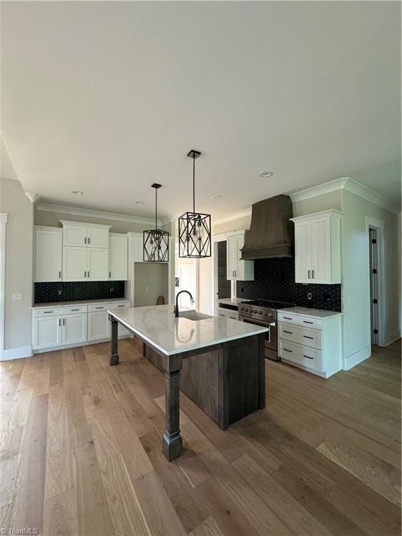 kitchen with high end range, white cabinetry, custom exhaust hood, and a spacious island