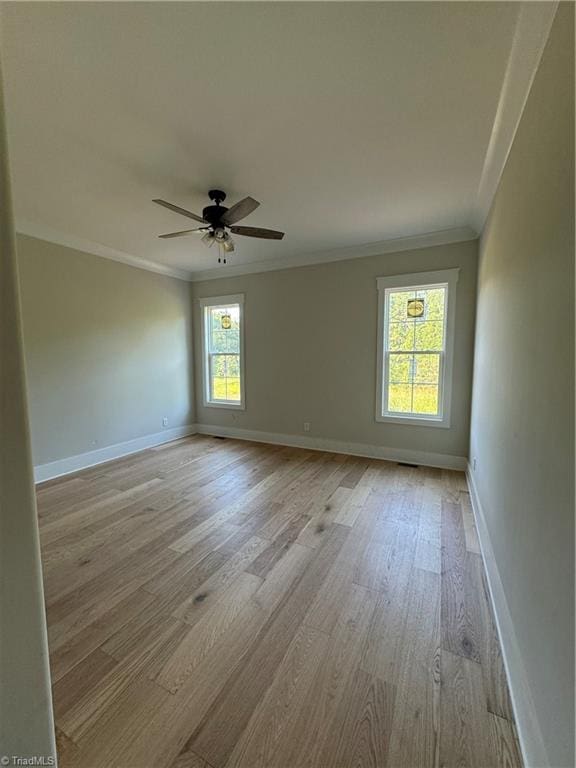 empty room with ornamental molding, a wealth of natural light, ceiling fan, and light wood-type flooring