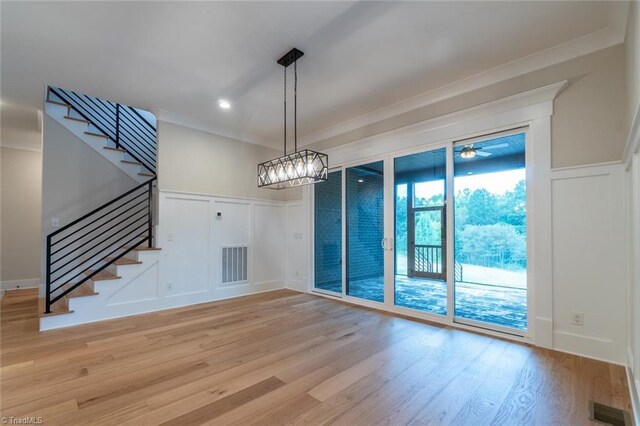 staircase featuring wood-type flooring, ornamental molding, and a chandelier