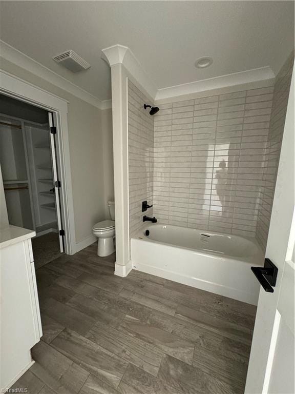 full bathroom with wood-type flooring, tiled shower / bath combo, ornamental molding, vanity, and toilet