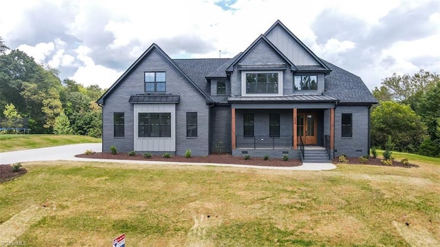 view of front facade featuring a porch, a standing seam roof, a front lawn, board and batten siding, and brick siding