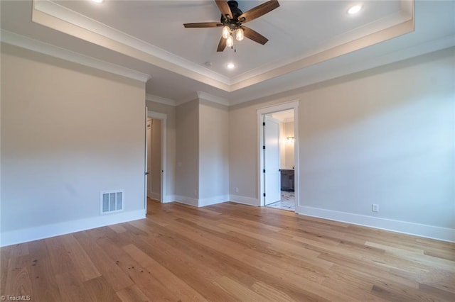 spare room with a raised ceiling, crown molding, ceiling fan, and light hardwood / wood-style flooring