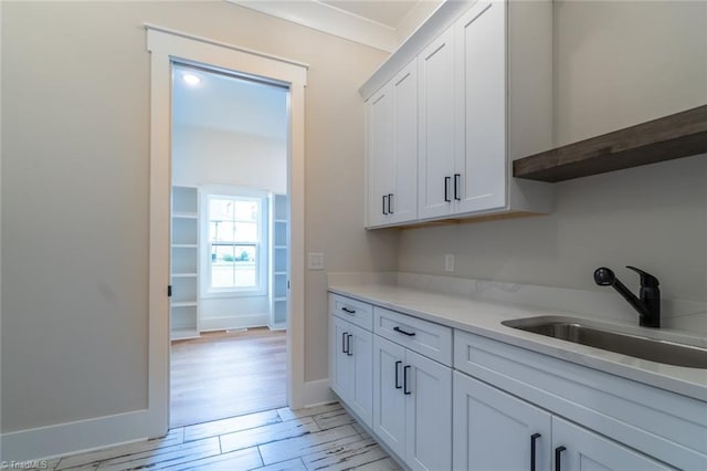 kitchen with white cabinets, light wood-type flooring, and sink