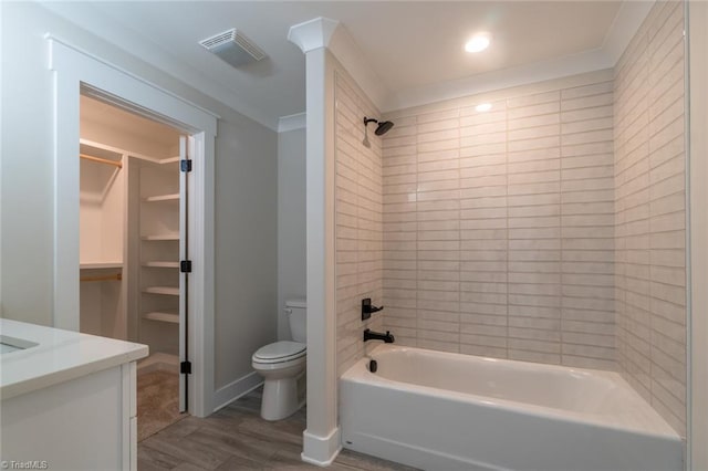 full bathroom featuring vanity, crown molding, hardwood / wood-style flooring, toilet, and tiled shower / bath