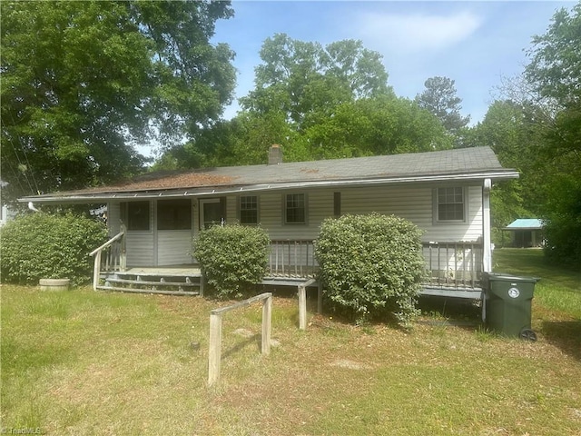 rear view of property with a chimney, a yard, a porch, and a shingled roof