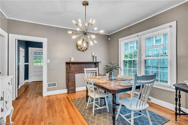 dining room with a chandelier, healthy amount of natural light, crown molding, baseboards, and light wood-style flooring