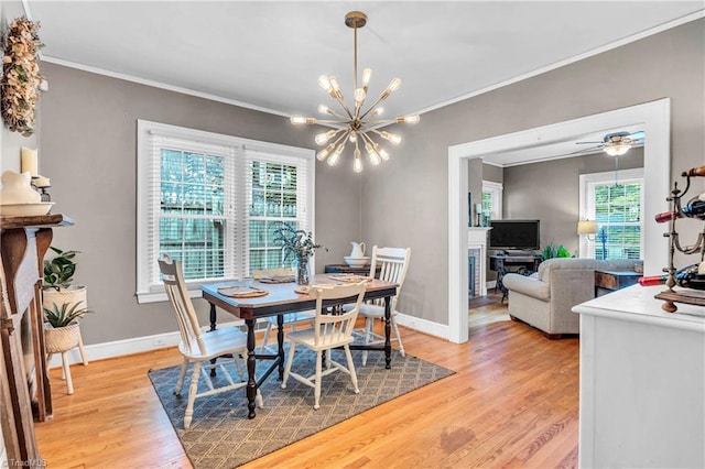 dining room with light wood-style flooring, plenty of natural light, a chandelier, crown molding, and baseboards