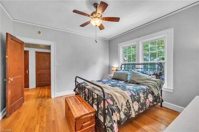 bedroom with light wood-style floors, baseboards, crown molding, and ceiling fan