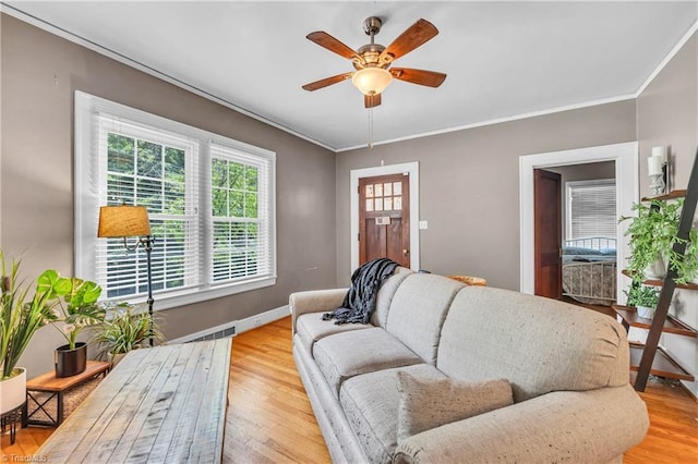 living area with ceiling fan, ornamental molding, baseboards, and light wood-style floors