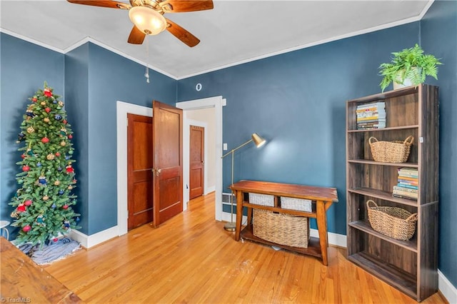 interior space featuring ceiling fan, wood finished floors, ornamental molding, and baseboards