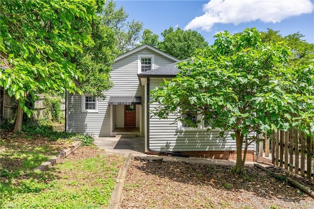 back of house featuring fence and a shingled roof