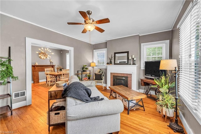 living room featuring a fireplace, wood finished floors, a ceiling fan, ornamental molding, and baseboards