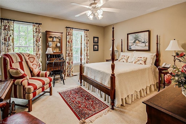 carpeted bedroom with ceiling fan and a textured ceiling