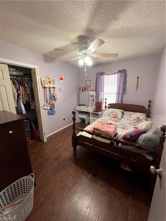 bedroom with dark wood-type flooring, a textured ceiling, ceiling fan, and a closet