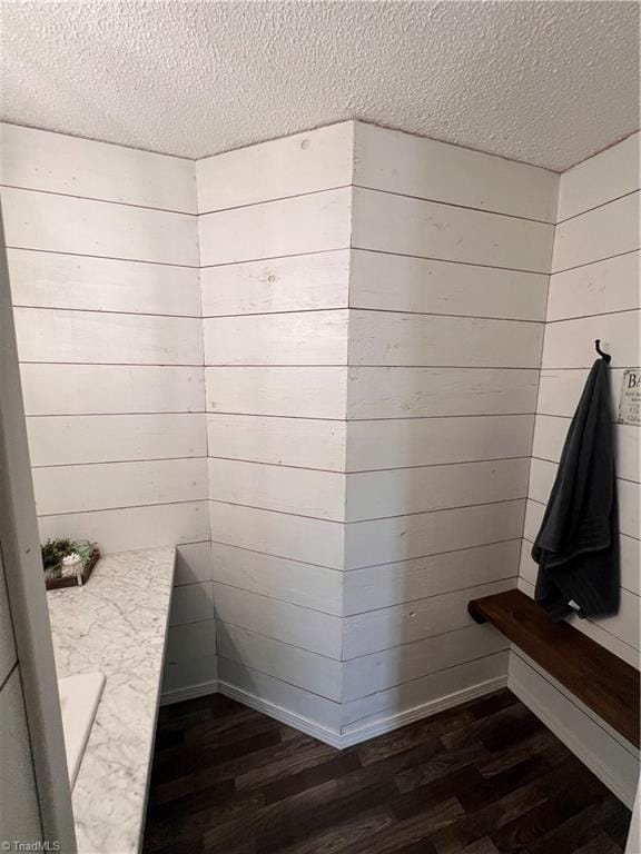 bathroom with hardwood / wood-style floors, a textured ceiling, and wooden walls