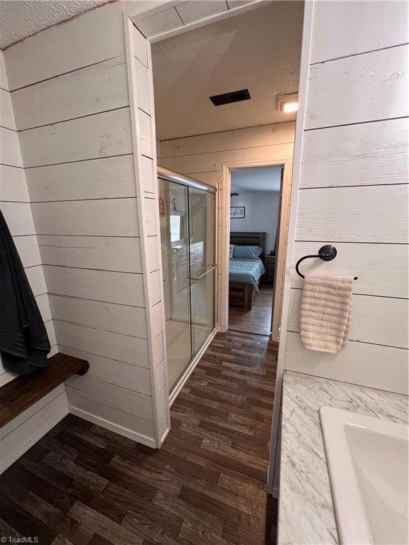 bathroom with hardwood / wood-style floors, a textured ceiling, and wood walls