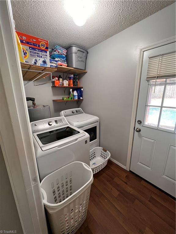 clothes washing area featuring dark wood-type flooring, a textured ceiling, and washer and clothes dryer