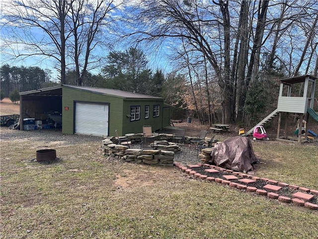 view of yard with a garage, an outdoor structure, and an outdoor fire pit