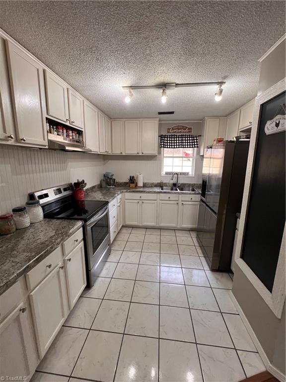 kitchen with stainless steel electric range oven, extractor fan, sink, white cabinets, and fridge with ice dispenser