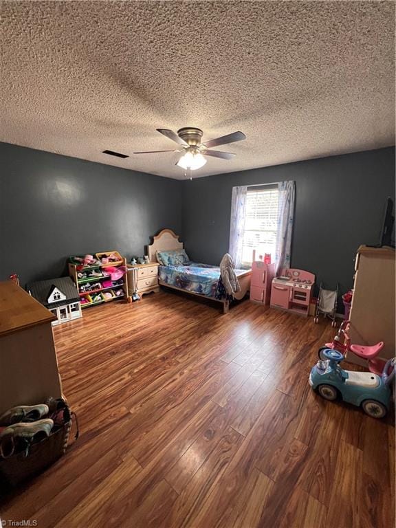 bedroom with ceiling fan, hardwood / wood-style floors, and a textured ceiling