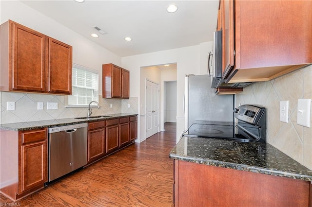 kitchen featuring stainless steel appliances, dark stone counters, a sink, visible vents, and dark wood-style floors