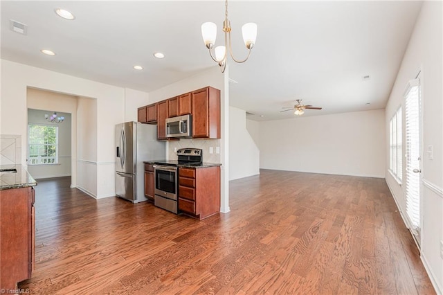 kitchen featuring brown cabinets, dark wood finished floors, stainless steel appliances, visible vents, and hanging light fixtures