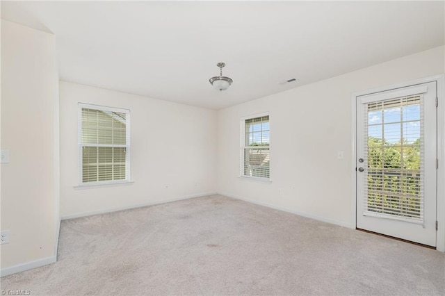 unfurnished room with baseboards, visible vents, and light colored carpet