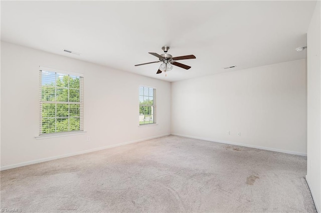 spare room featuring light colored carpet, visible vents, and baseboards