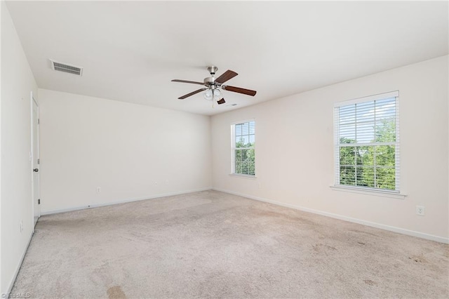 empty room with a ceiling fan, visible vents, light carpet, and baseboards