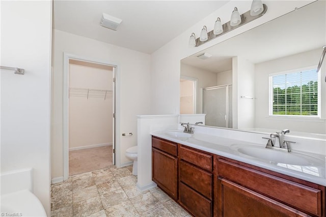 full bathroom featuring double vanity, a stall shower, a spacious closet, and a sink