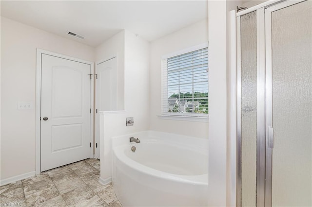 bathroom featuring a stall shower, baseboards, visible vents, and a garden tub