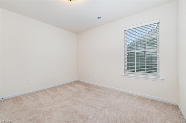 spare room featuring light carpet, visible vents, and baseboards