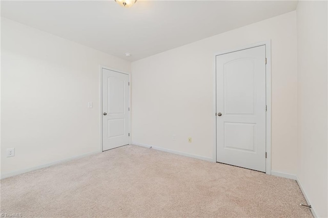 spare room featuring light carpet and baseboards