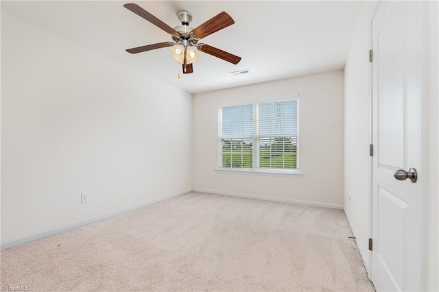 spare room featuring light carpet, a ceiling fan, visible vents, and baseboards