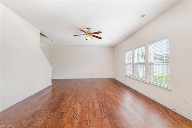 unfurnished room with ceiling fan, dark wood finished floors, and baseboards