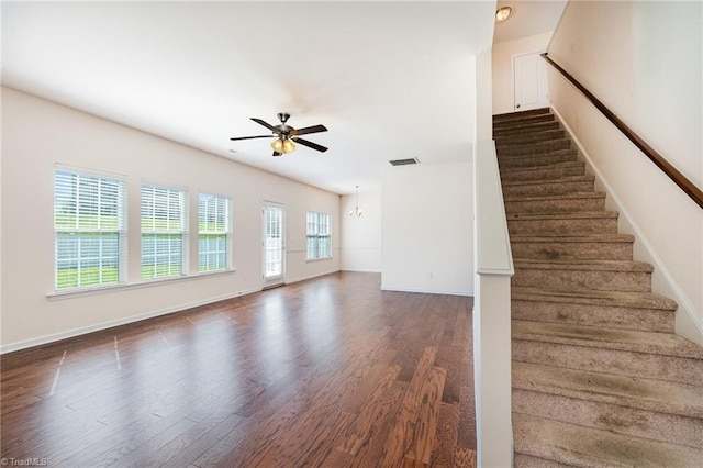 unfurnished living room featuring dark wood-style floors, ceiling fan, stairs, and visible vents