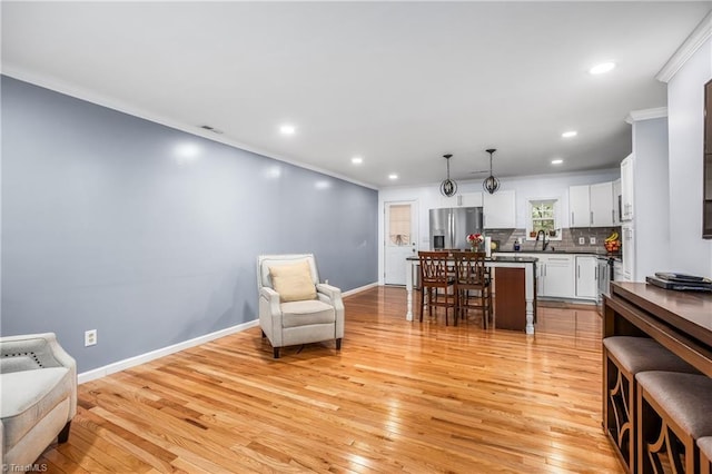 interior space with sink, light hardwood / wood-style flooring, and ornamental molding