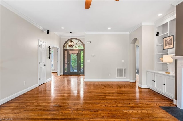 interior space with a ceiling fan, visible vents, built in features, arched walkways, and wood finished floors