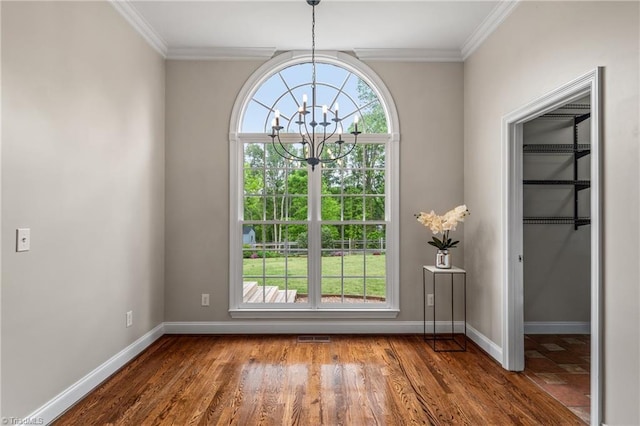 interior space featuring crown molding, visible vents, wood finished floors, baseboards, and a notable chandelier