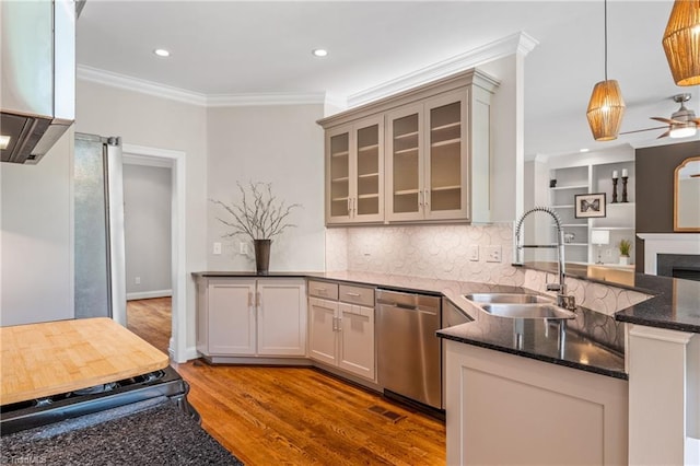kitchen with ornamental molding, a peninsula, wood finished floors, a sink, and dishwasher