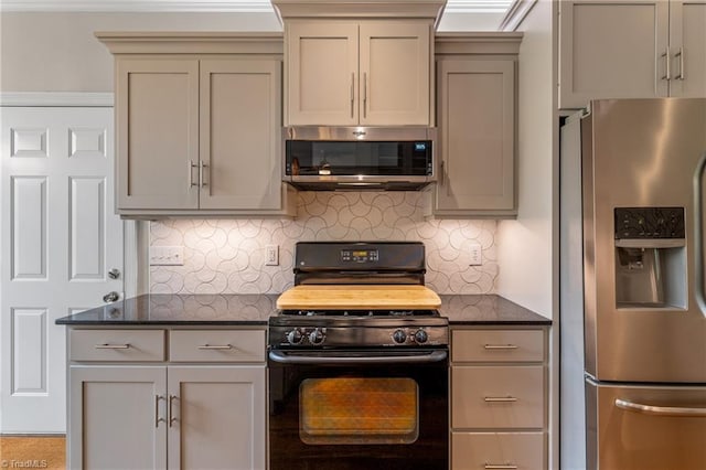 kitchen featuring gray cabinetry, backsplash, stainless steel appliances, and dark stone countertops