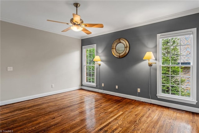 spare room featuring crown molding, visible vents, wood finished floors, baseboards, and a ceiling fan