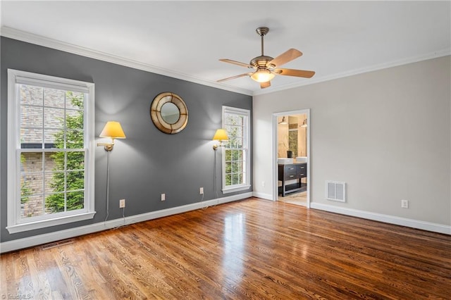 spare room with a healthy amount of sunlight, baseboards, wood finished floors, and visible vents