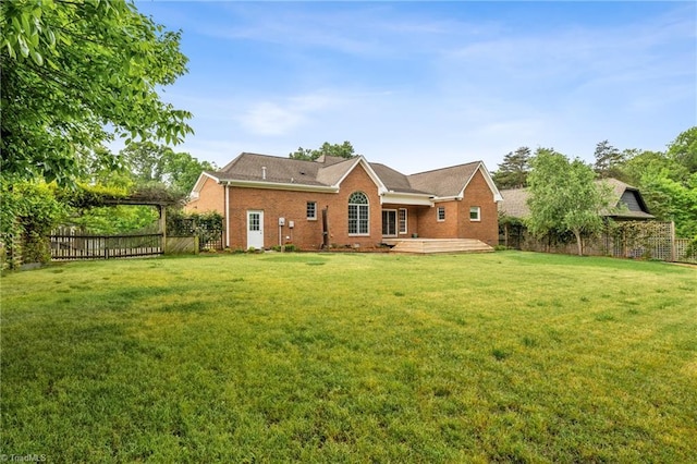 rear view of property featuring fence, a wooden deck, a yard, and brick siding