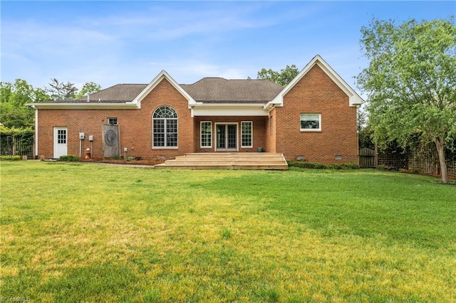 back of property featuring brick siding, a lawn, fence, and a deck