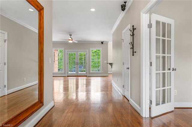 hall featuring crown molding, baseboards, french doors, and wood finished floors